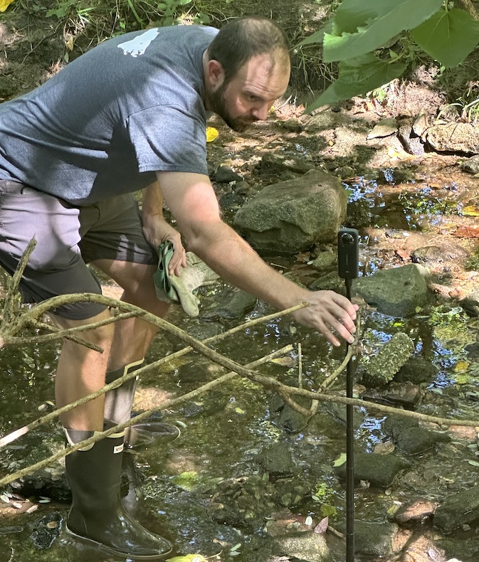 Nathan recording 360-degree video in a local stream with an Insta360 X3 camera mounted on a tripod